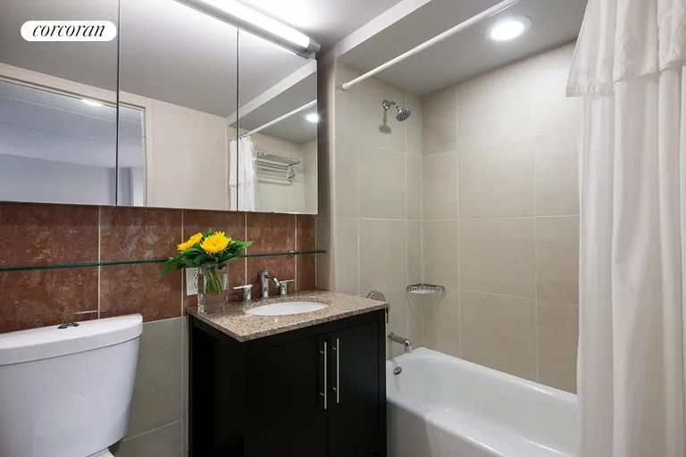 New York City Real Estate | View 555 West 23rd Street, S7M | Floor-to-ceiling tiled bathroom w/mirrored cabinet | View 4