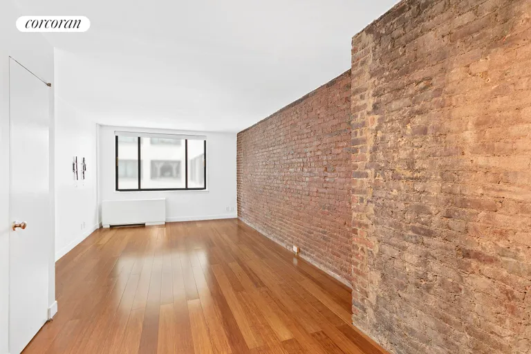 New York City Real Estate | View 77 Bleecker Street, 821E | Spacious Living Room with exposed brick wall. | View 6