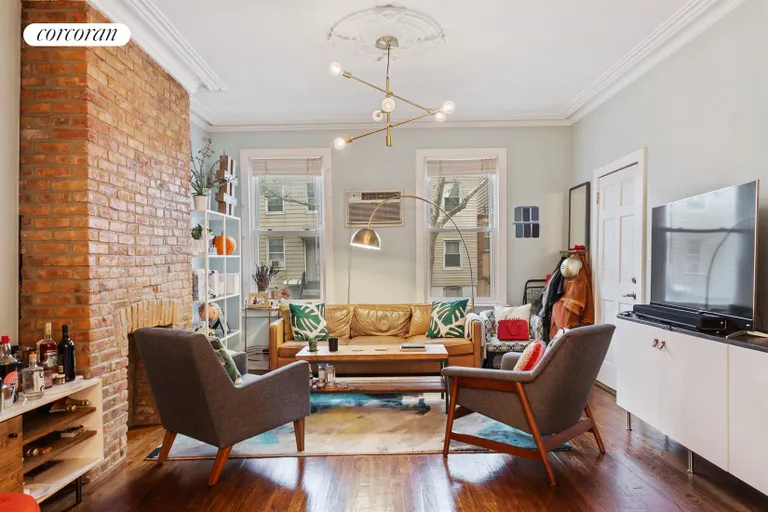 New York City Real Estate | View 68 Devoe Street | Welcoming living room w/ exposed brick fireplace | View 2